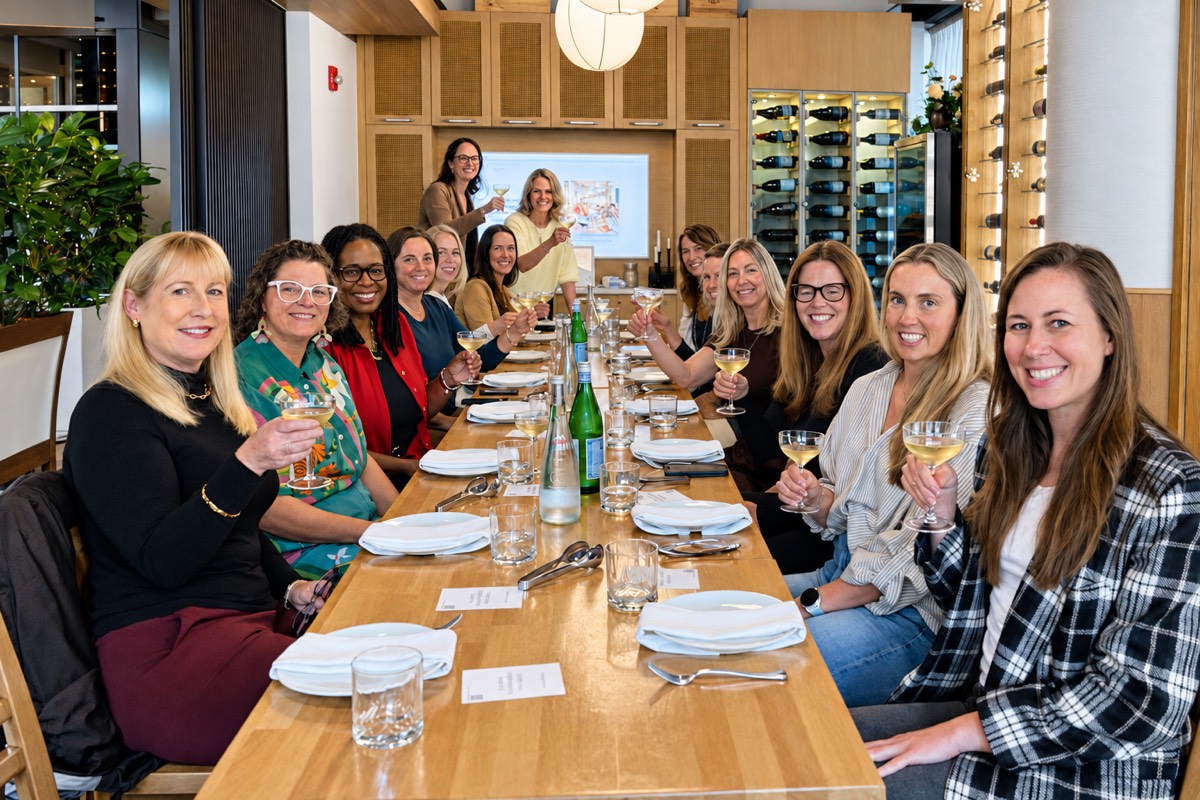 Group of women around a long table raising glasses at Bubbles and Bots Vol. 3